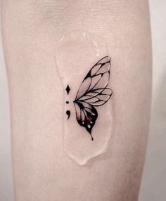 a small black and white butterfly tattoo on the side of a woman's thigh