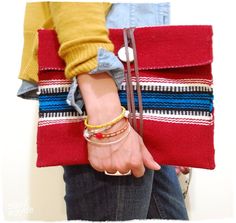 a woman's hand holding onto a red, white and blue striped clutch bag