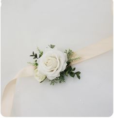 a bridal bouquet with white roses and greenery tied to the back of it