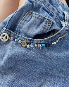 a peace sign is attached to the back of a pair of blue jeans with beads