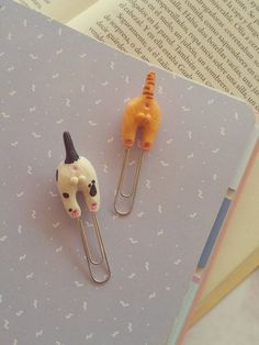 two paper clips with animals on them sitting next to an open book