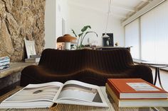 an open book sitting on top of a couch next to a table with two books