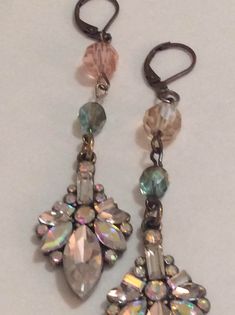 two pairs of earrings are shown on a white surface, one is made out of glass and the other has multicolored beads