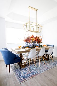 a dining room table with blue chairs and an area rug in front of the table