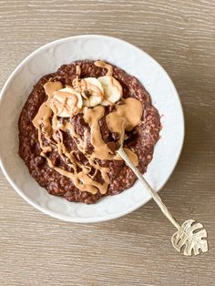 a bowl of oatmeal with peanut butter and bananas on top, sitting on a table