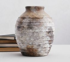 a vase sitting on top of a table next to a stack of hardback books