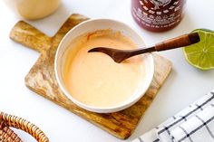 a wooden spoon sitting in a bowl on top of a cutting board next to some condiments