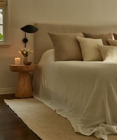 a bed with white sheets and pillows next to a window