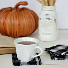 a cup of coffee sitting on top of a table next to an open book and a pumpkin