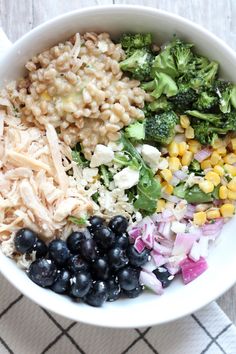 a bowl filled with rice, broccoli, blueberries and other food items