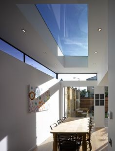 a dining room table and chairs under a skylight