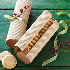 an open box of crackers next to a roll on a wooden table with ribbon