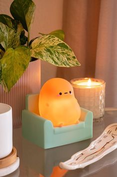 a small light sitting on top of a table next to a potted plant and candle