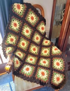 a crocheted sunflower blanket sitting on top of a wooden chair