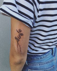 a woman's arm with a small flower tattoo on the back of her left arm