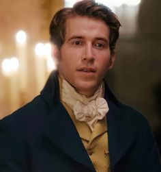 a man in a suit and bow tie looking off to the side with candles behind him