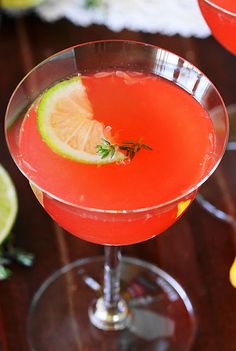 two glasses filled with red liquid and garnished with lime