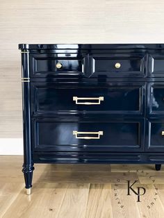 a dark blue dresser with brass handles and knobs on the drawers is sitting on a wooden floor