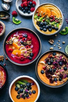 several bowls of food are arranged on a table with fruit, nuts and other foods