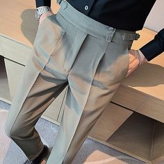 a person standing in front of a wooden desk wearing pants and black shirt with buttons