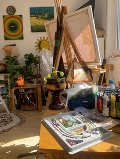 an artist's easel with art supplies on it in front of a window