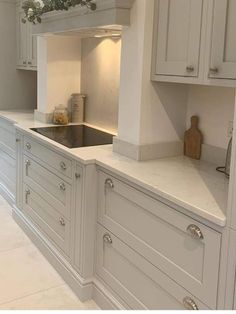 a kitchen with white cabinets and marble counter tops, an oven hood over the sink