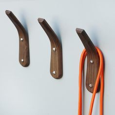 three wooden hooks with orange cords attached to them on the wall next to each other