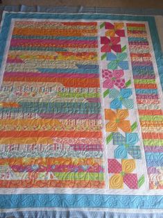 a quilted table runner with flowers and ribbons on the edges, in bright colors