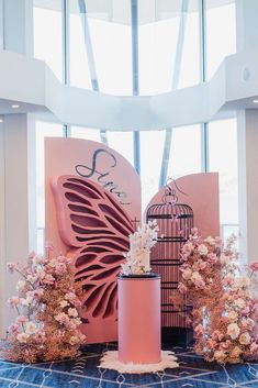 a birdcage with flowers on top of it next to a pink sign that says love