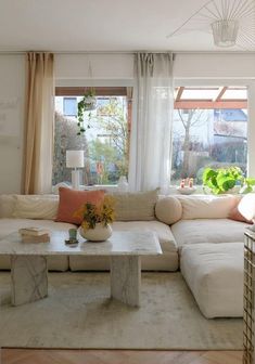 a living room filled with lots of furniture next to a large window covered in curtains