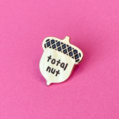 a metal pin with the words total nut on it sitting on a bright pink surface