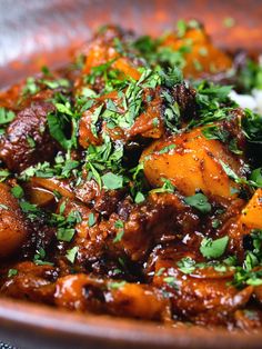 a brown bowl filled with food and garnished with parsley on the side