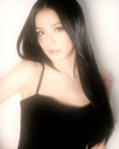 a woman with long black hair posing for the camera