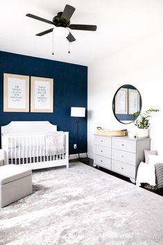 a baby's room with blue walls and white furniture