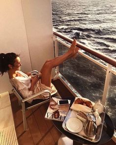 a woman sitting in a chair on top of a balcony next to an ocean view