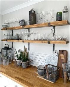 the shelves are filled with wine glasses and other kitchen utensils on wooden countertops