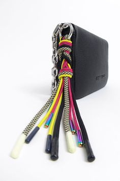 several different colored cords are attached to a black case on a white surface with a chain hanging from it's side