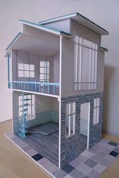 a paper model of a house with stairs and windows on top of a wooden floor