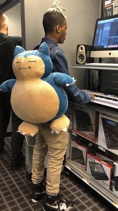 a man is standing in front of a computer with a stuffed animal on his back