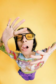 a woman with her hands in the air and wearing glasses on top of her head