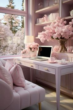 a desk with a laptop and pink flowers in the window sill next to it