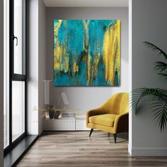 an abstract painting on the wall in a room with a yellow chair and potted plant