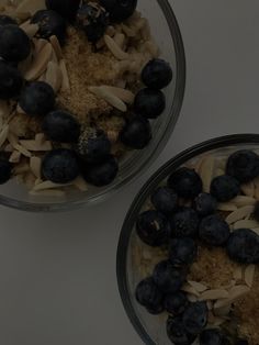 two bowls filled with blueberries and oats on top of a white countertop