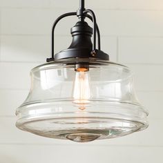 a clear glass light fixture hanging from a white brick wall in a kitchen or dining room