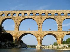 an old stone bridge spanning the width of a body of water with arches above it