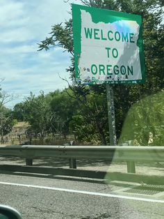 a welcome to oregon sign in front of a highway