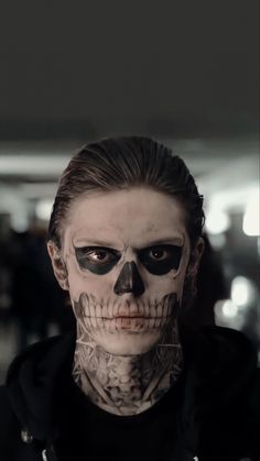 a man with makeup on his face is wearing a skull mask and looking at the camera