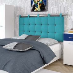 a bed with blue headboard and pillows in a white room next to a night stand