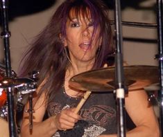 a woman with purple hair is playing drums