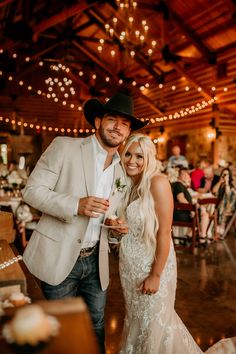 a bride and groom pose for a photo at their wedding reception in a rustic barn